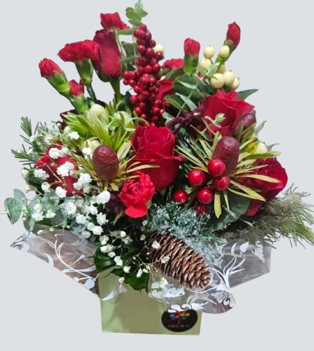 Bouquet of red flowers with greenery and berries in a box